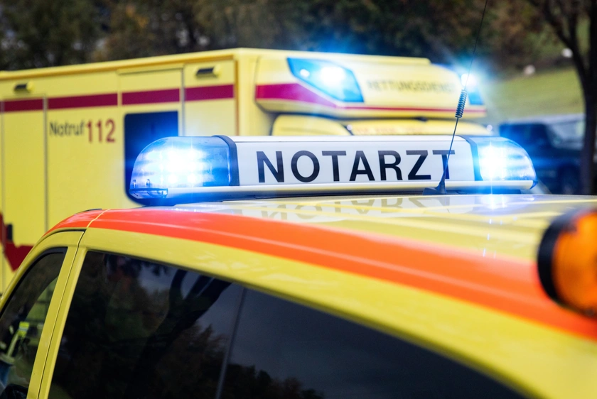 Martinshorn auf dem Dach eines Notarzteinsatzfahrzeuges mit Beschriftung "Notarzt" und dahinter stehend ein Rettungswagen.